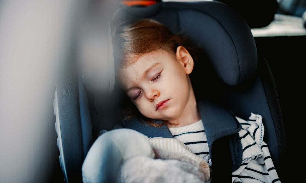 ett barn som sover i en bilstol (AI text)