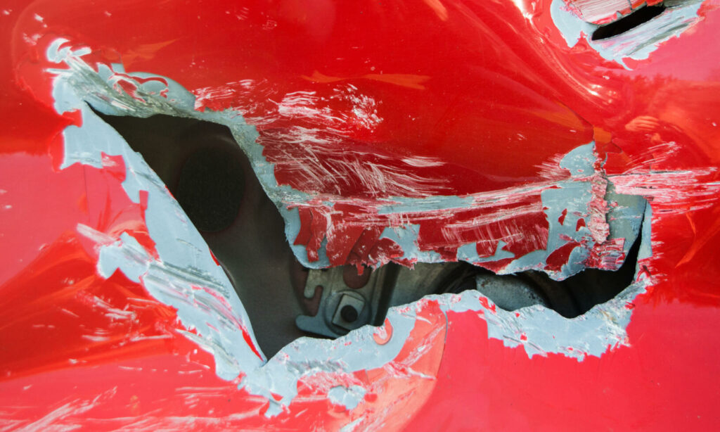 En röd bil med ett hål i huven. (AI text)