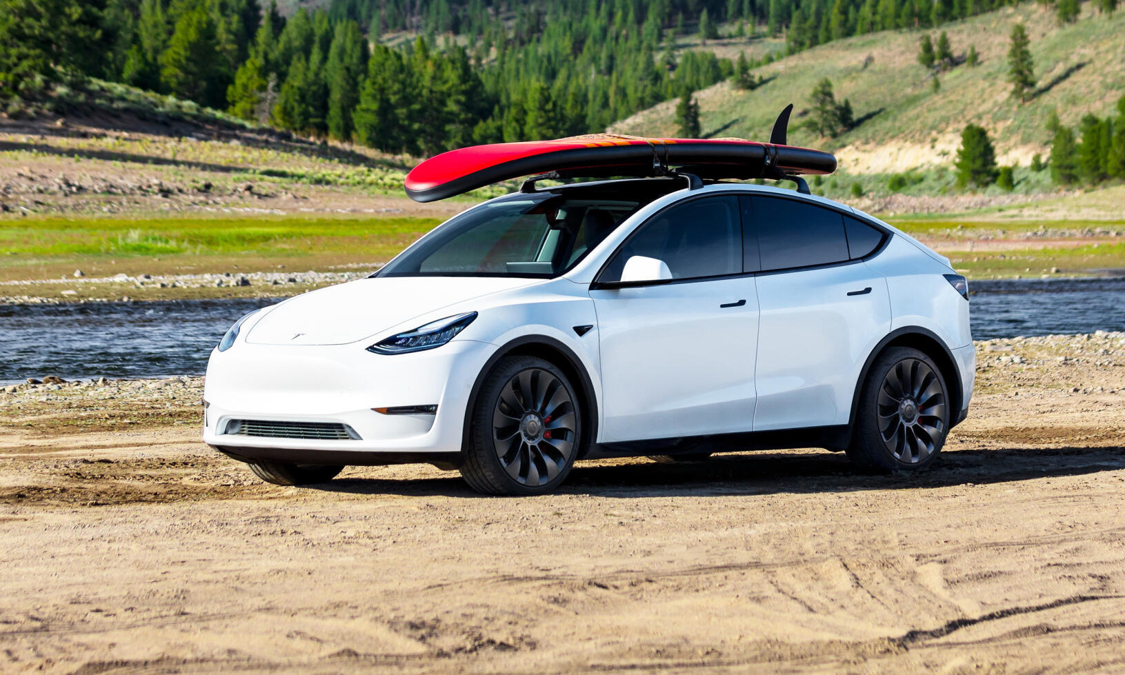 En Tesla Model Y parkerad på en grusväg nära en bergsida. (AI text)