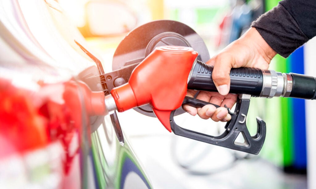 En man tankar sin bil på en bensinstation. (AI text)