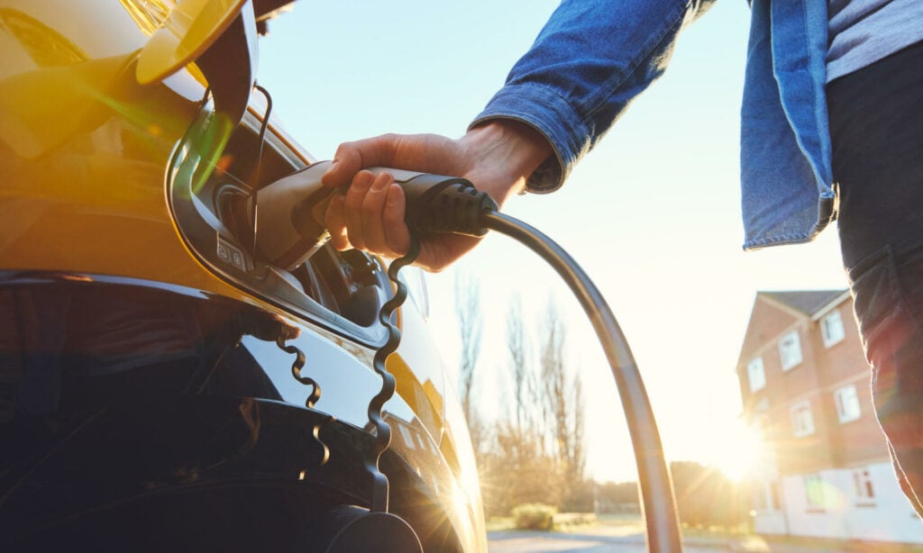 En man laddar sin elbil. (AI text)