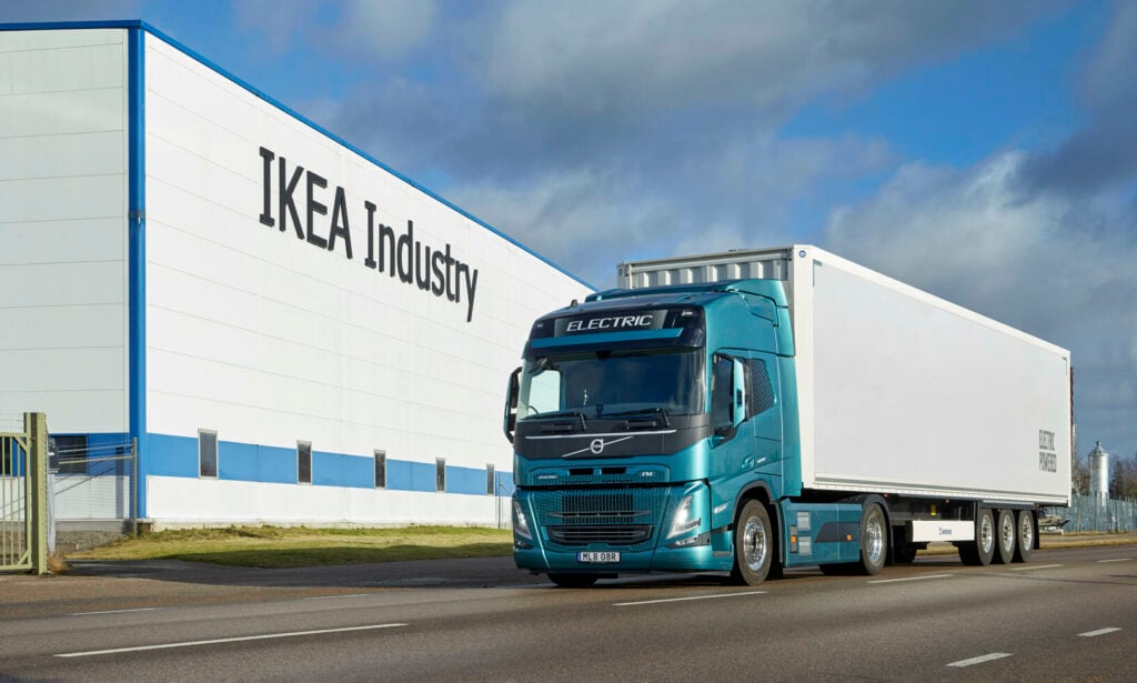 En Volvo-lastbil kör förbi en fabrik. (AI text)