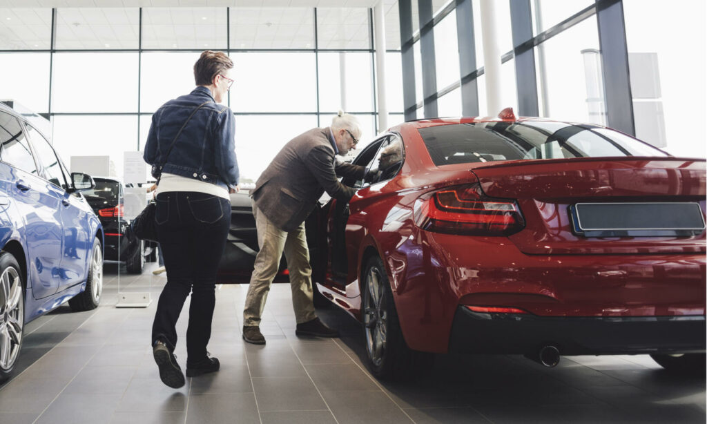 En kvinna och en man tittar på bilar i en bilstation. (AI text)