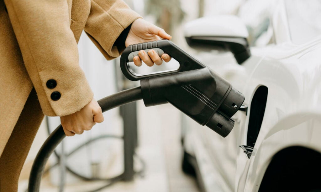 En kvinna fyller på sin bil med bränsle på en bensinstation. (AI text)