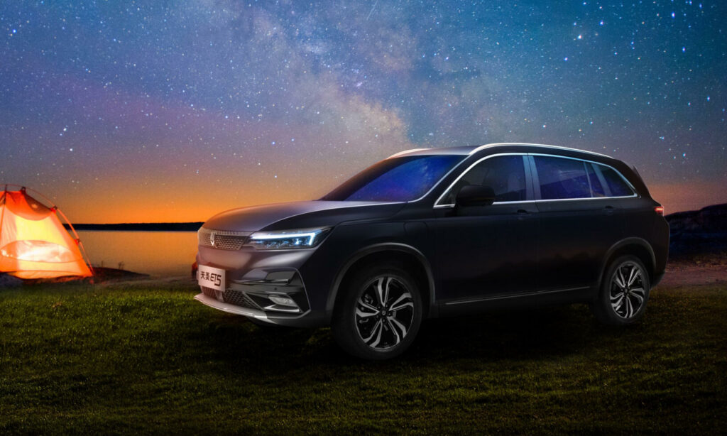 En SUV parkerad på en gräsmatta med en tält i bakgrunden. (AI text)