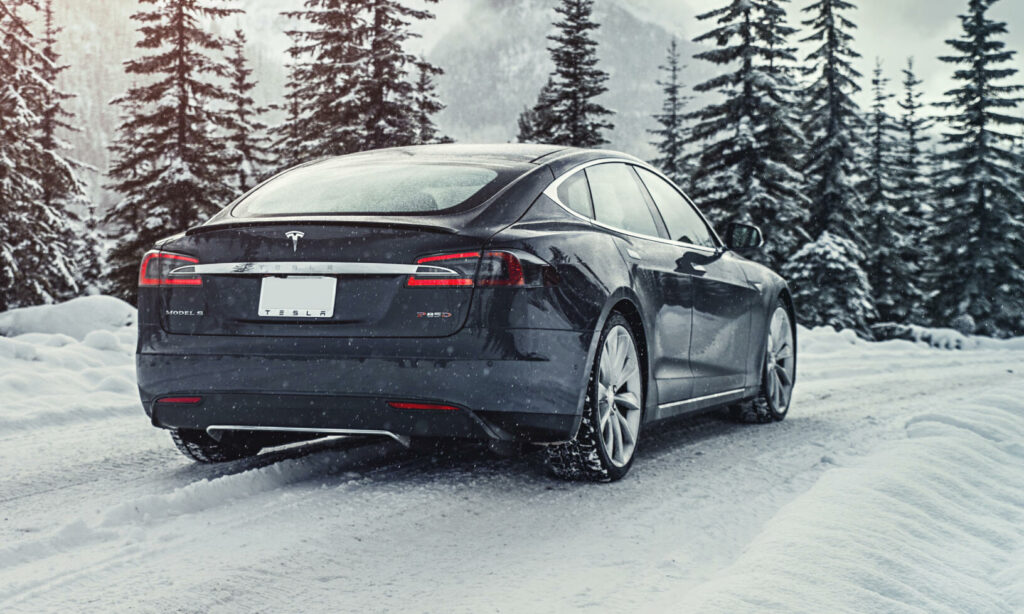 En Tesla Model S kör på snöig väg i bergen. (AI text)