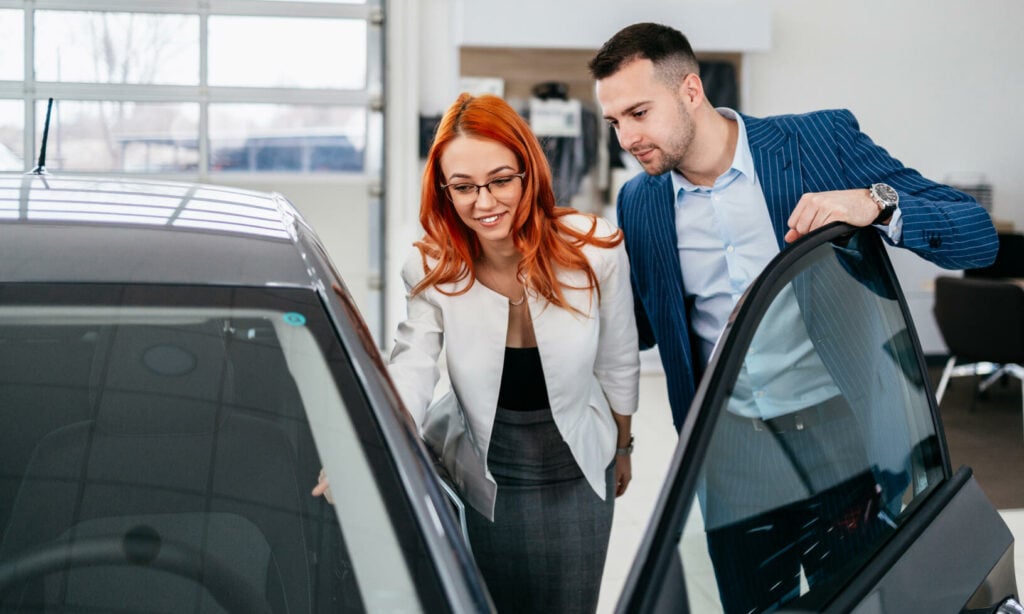 ett par tittar på en bil i en showrum (AI text)