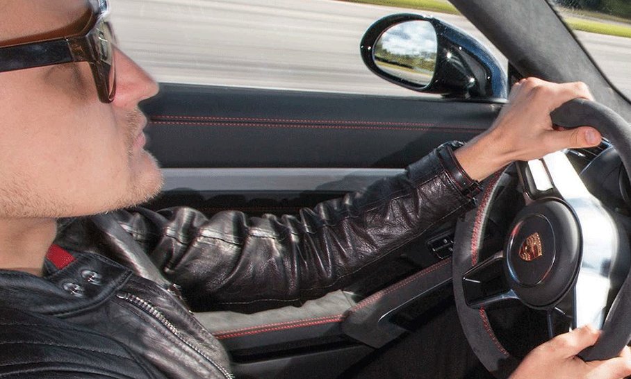 En man i läderskjorta kör en sportbil. (AI text)
