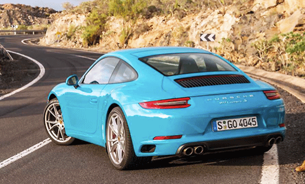 En blå Porsche 911 GTS körs nedför en bergväg. (AI text)