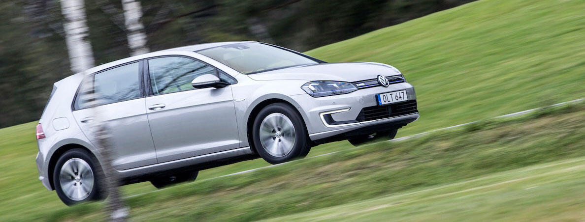 En Volkswagen Golf E - EV kör nerför en backe. (AI text)