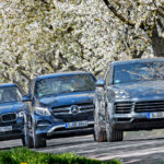 Bilar kör nedför en väg med trädkulturer i bakgrunden. (AI text)