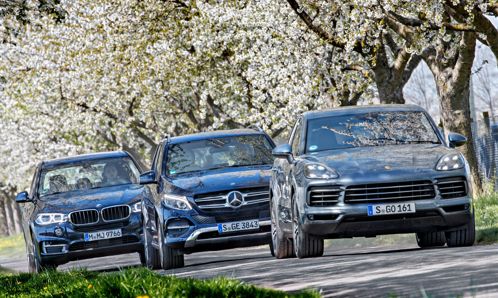 Bilar kör nedför en väg med trädkulturer i bakgrunden. (AI text)