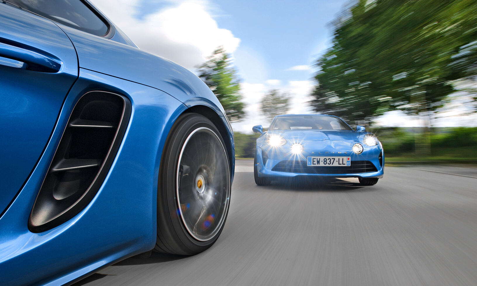 En blå Porsche Cayman kör nedför en väg. (AI text)