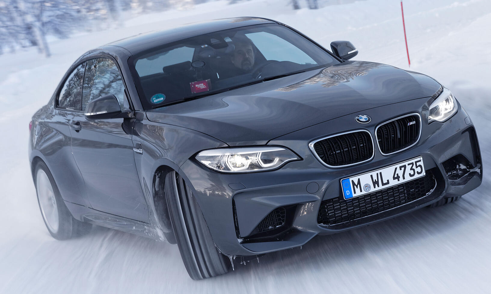 BMW M2 kör på snöiga vägar (AI text)