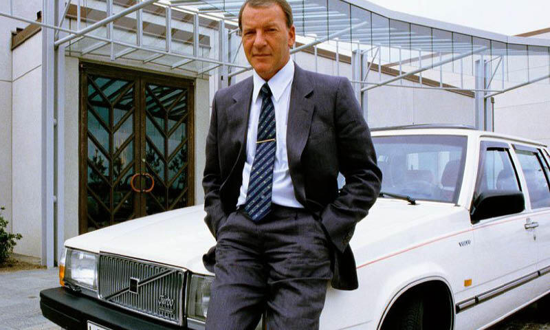 En man i kostym står bredvid en bil. (AI text)