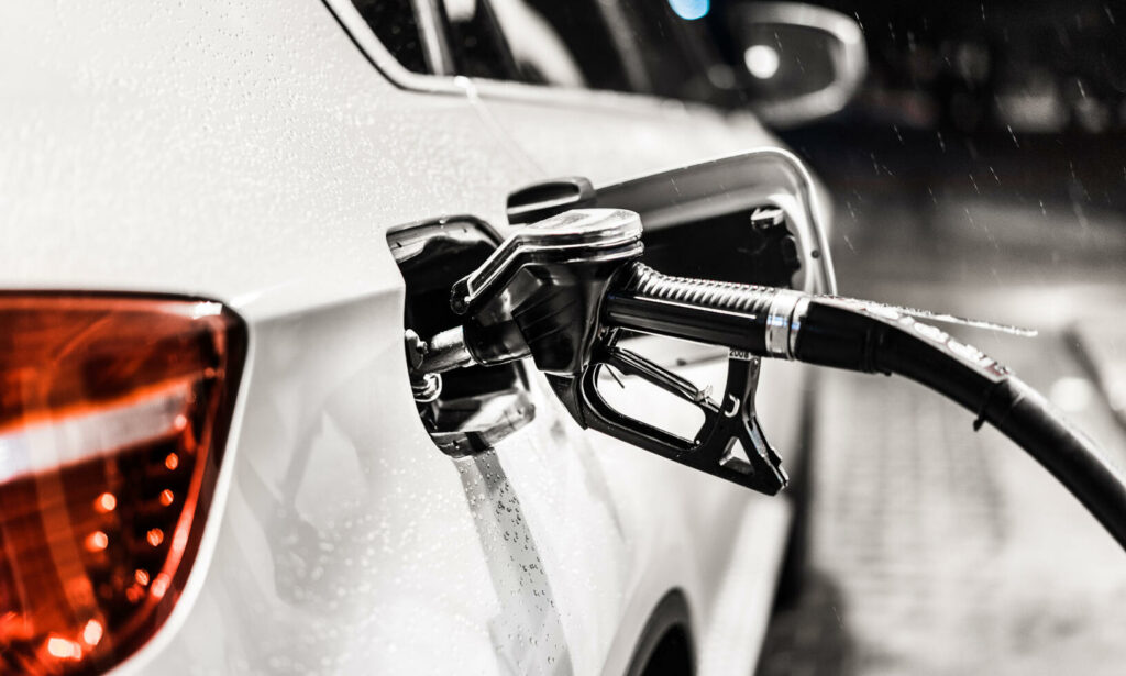 En vit bil står parkerad vid en bensinstation. (AI text)