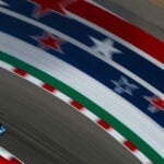 En racebil kör nedför en bana med amerikanska flaggor. (AI text)