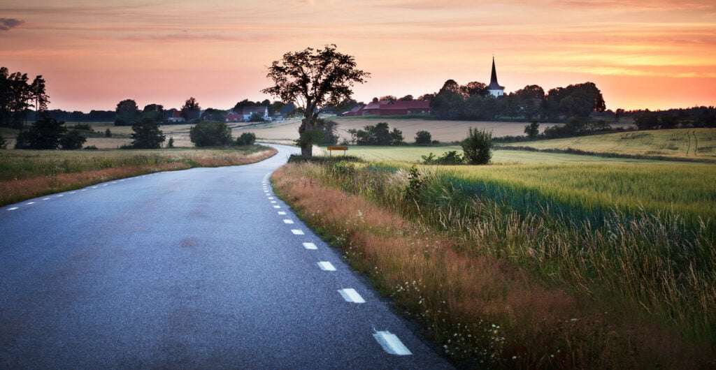 En landsväg vid solnedgången i landsbygden. (AI text)