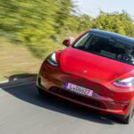 Tesla Model 3 kör längs en landsväg. (AI text)