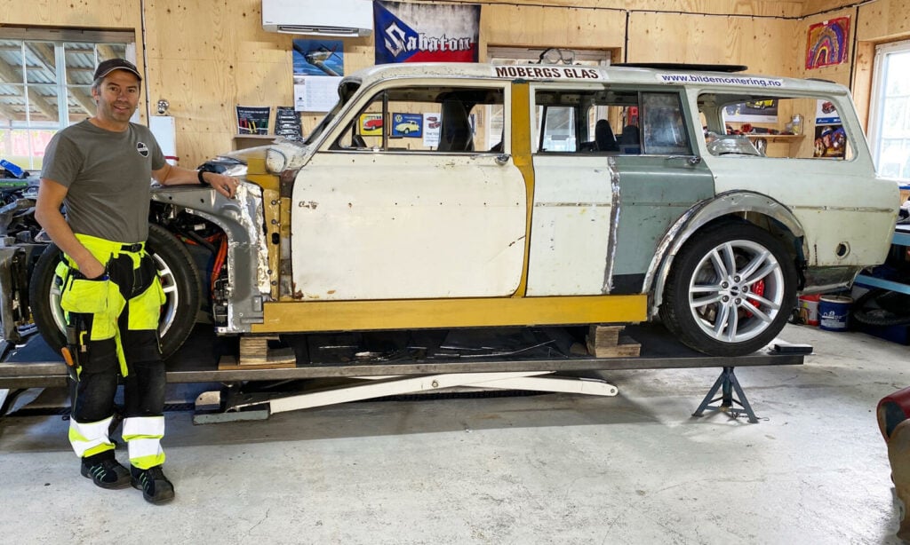 En man står bredvid en bil i en garage. (AI text)