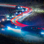 En bil kör nerför en bergsväg på natten. (AI text)