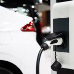 En vit bil är uppkopplad till en elbilsladdstation. (AI text)