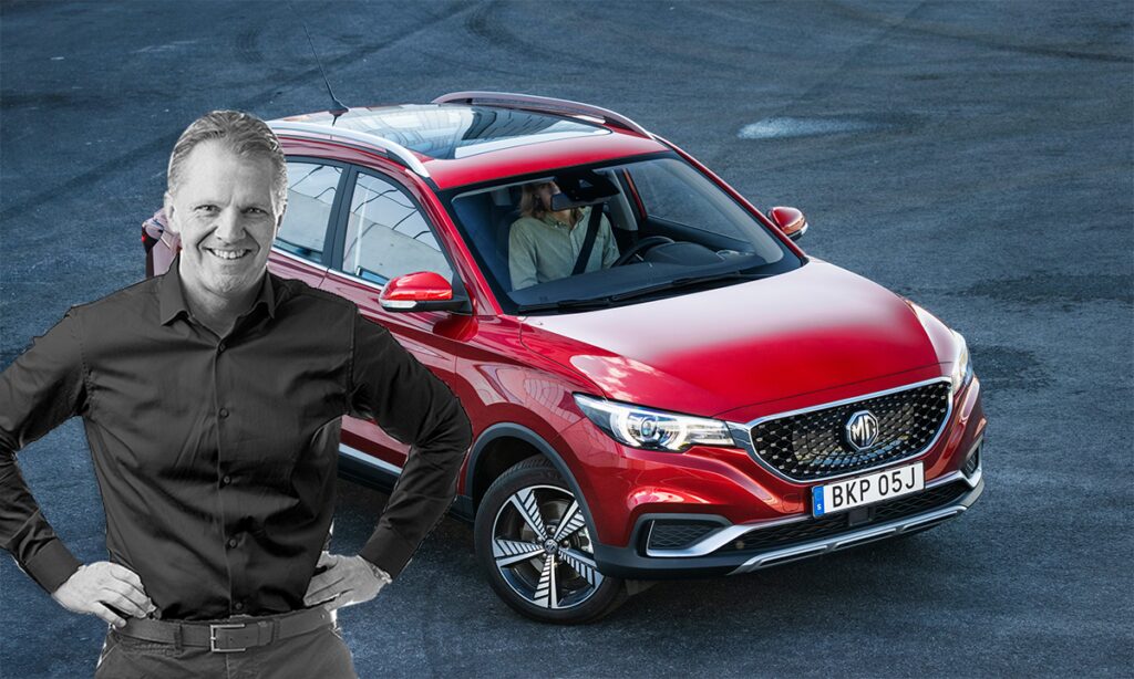 En man står bredvid en röd SUV. (AI text)