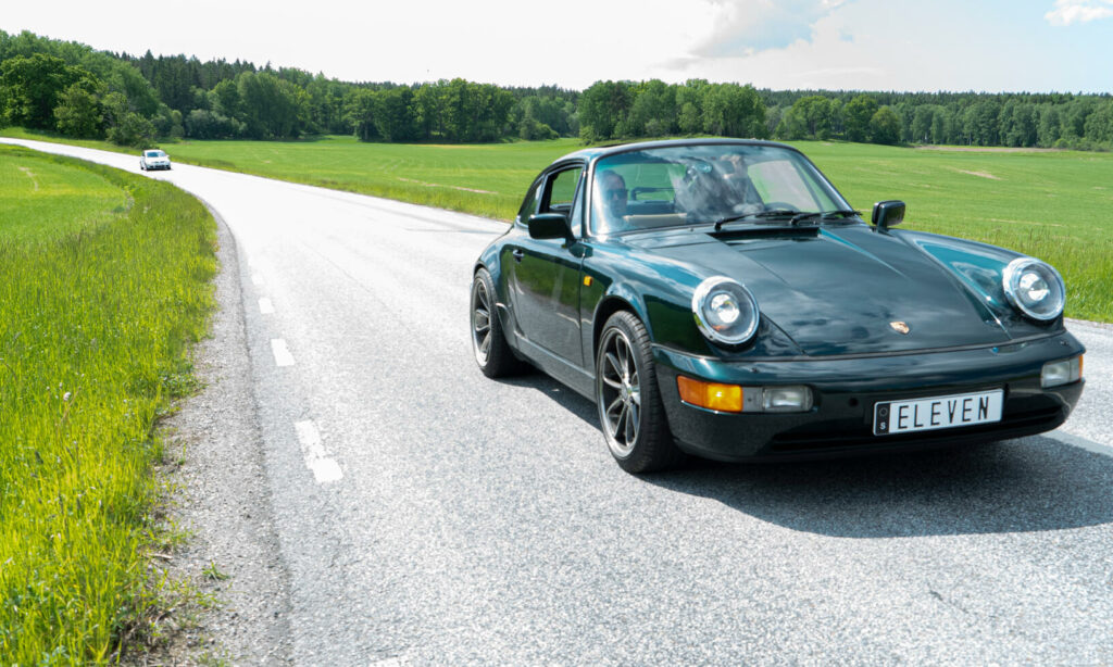 En grön Porsche 911 kör längs en landsväg. (AI text)