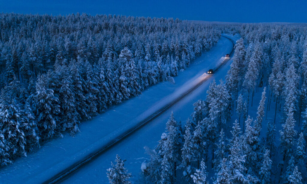 Luftbild över en snöig väg i skogen (AI text)