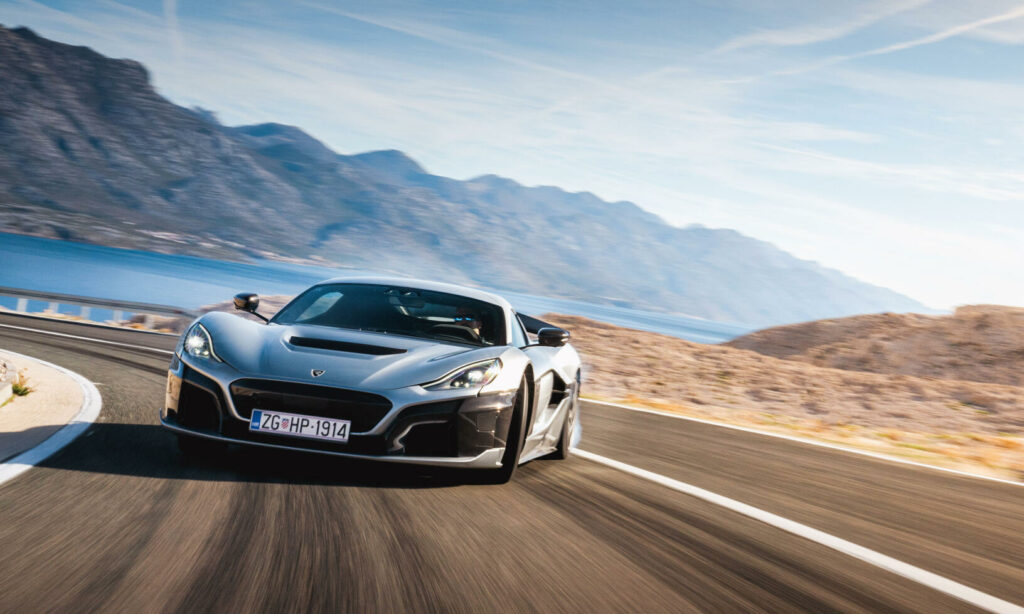 En silverfärgad sportbil kör nerför en bergsväg. (AI text)