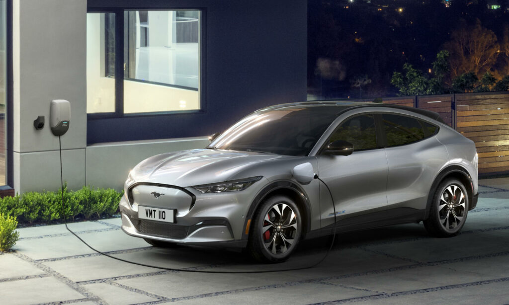 En silverfärgad elbil parkerad framför en villa. (AI text)