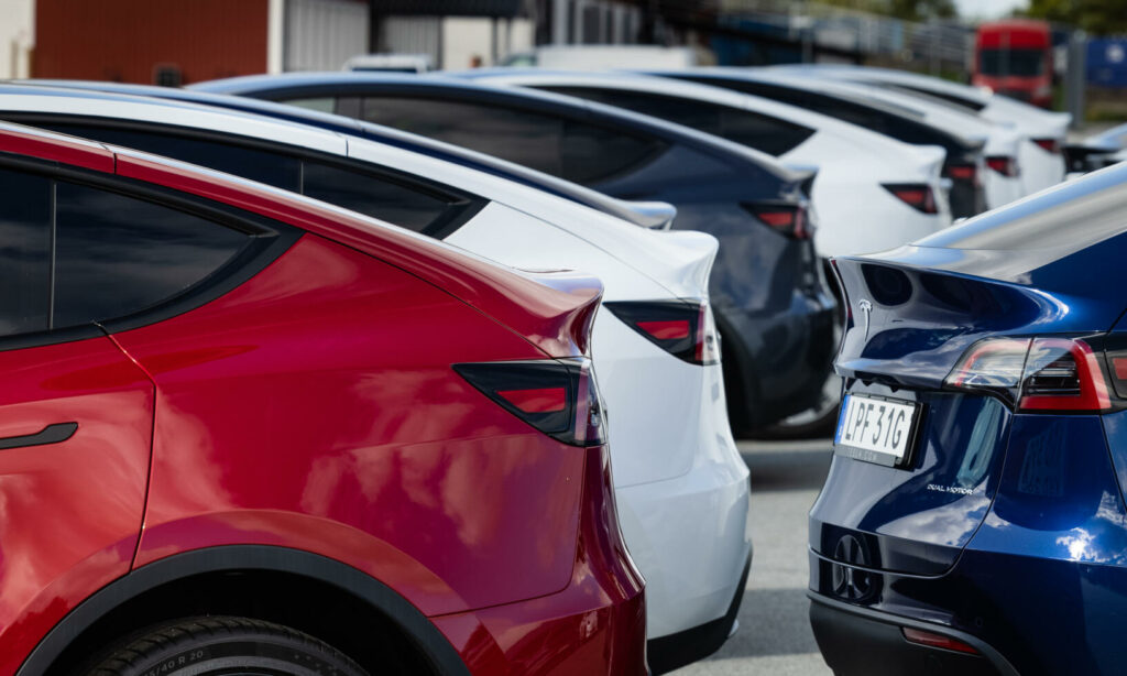 En rad parkerade Tesla Model S-bilar i ett parkeringsområde. (AI text)