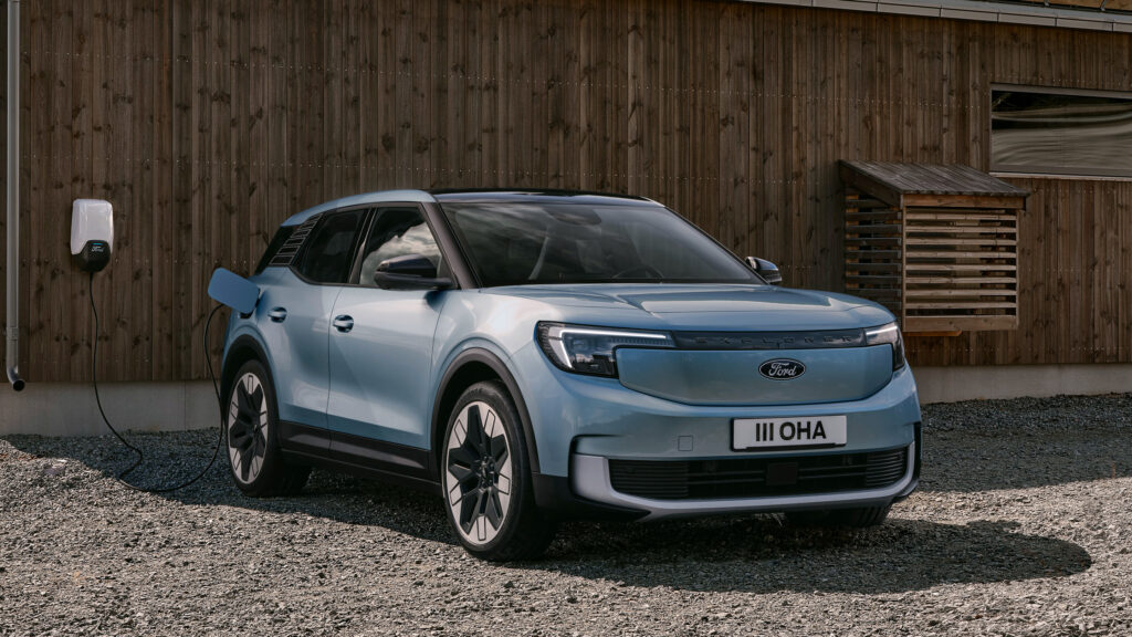 En blå SUV parkerad framför ett träbyggnad. (AI text)