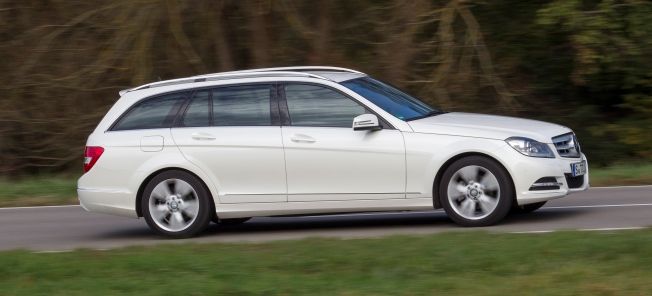 En Mercedes C-klass vagn kör längs en landsväg. (AI text)