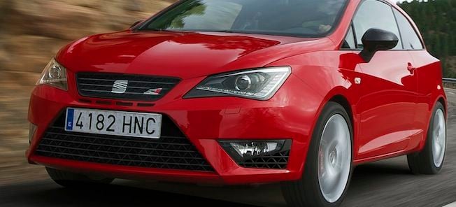 En röd bil kör nerför en bergsväg. (AI text)