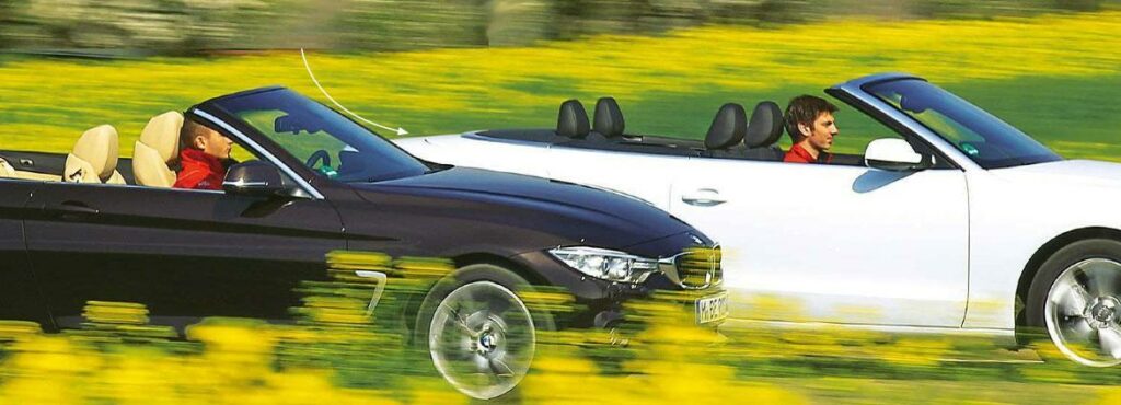 Två konvertibilar kör nedför en väg. (AI text)