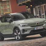 Mossgrön Volvo XC40 snett framifrån kör i stadsmiljö.
