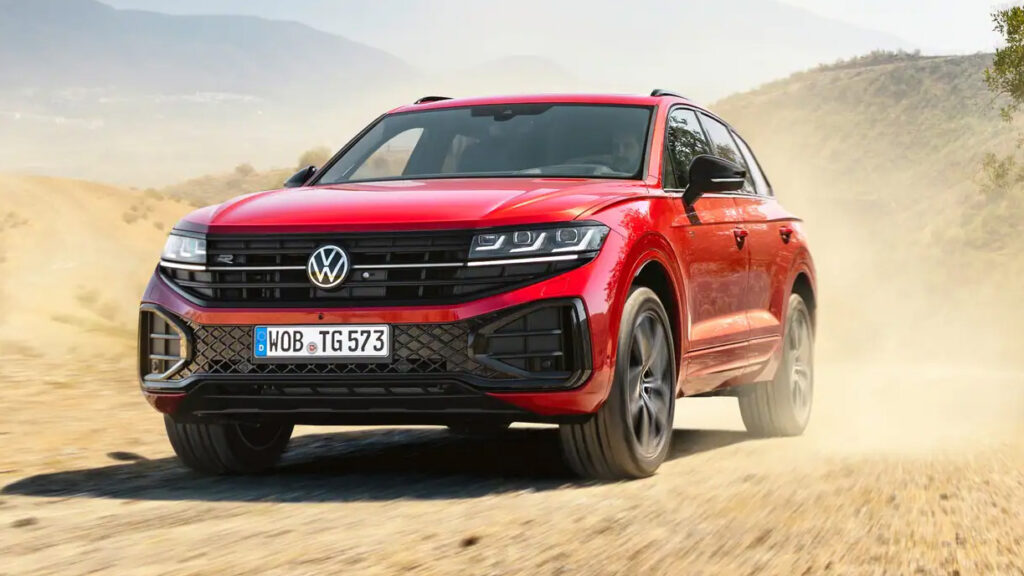 En röd Volkswagen Atlas kör nedför en grusväg. (AI text)