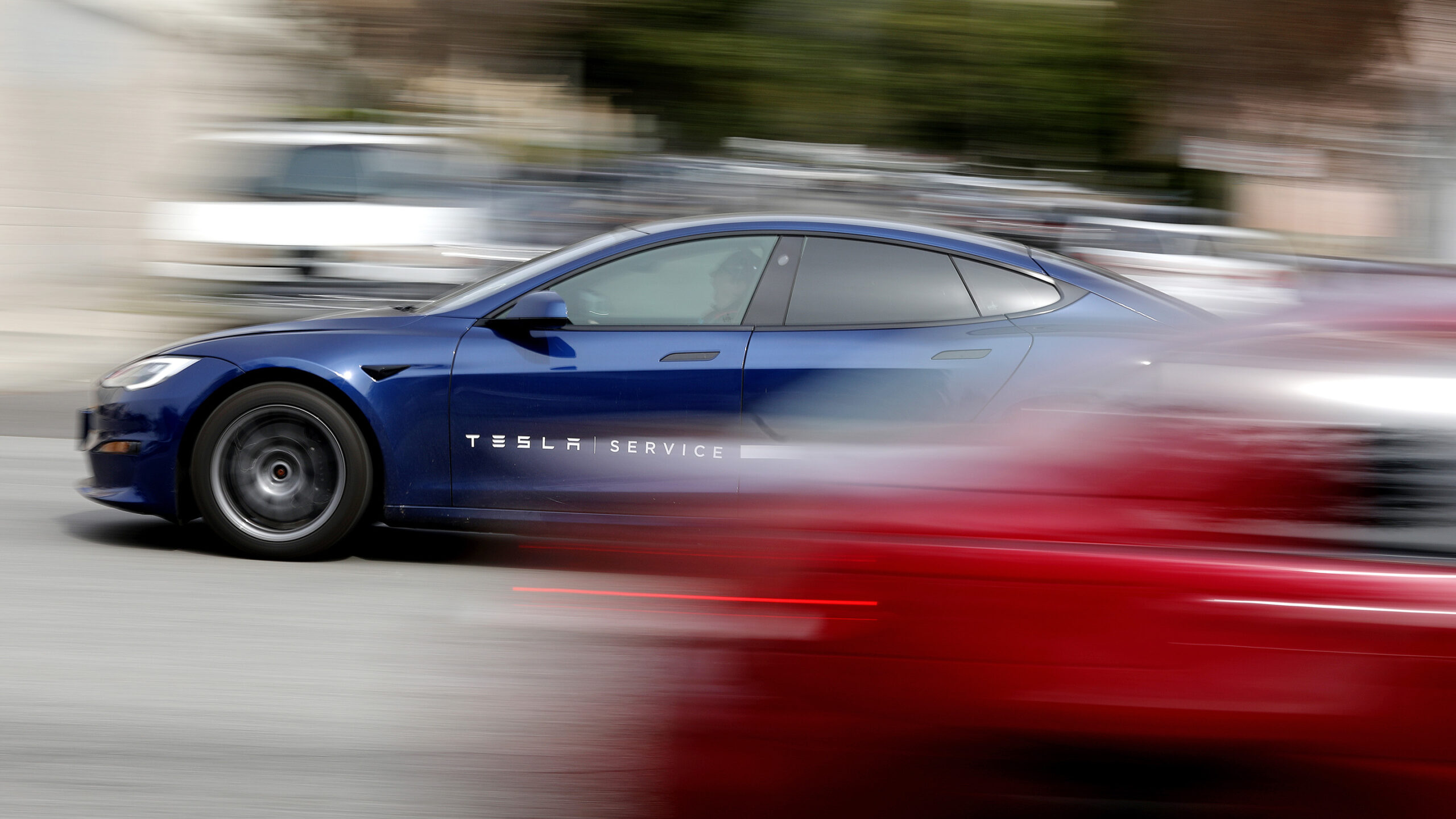 En Tesla Model S kör nerför en gata. (AI text)