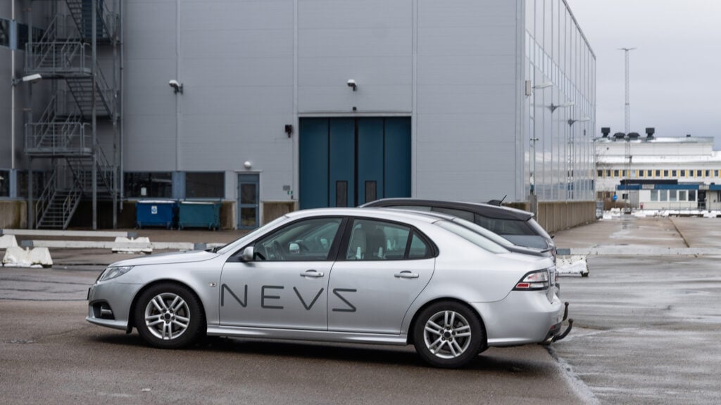 En bil parkerad framför ett byggnad. (AI text)