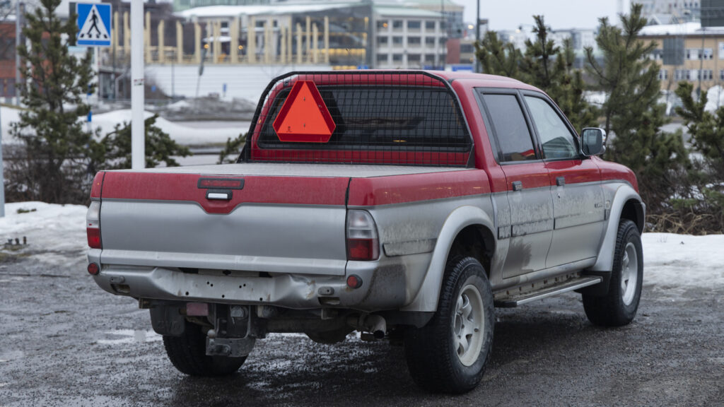 En röd lastbil parkerad på en snöig gata. (AI text)