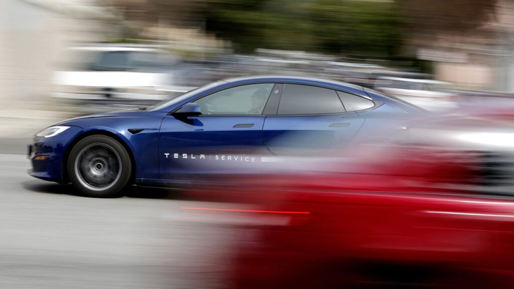 En Tesla Model S kör ner en gata. (AI text)