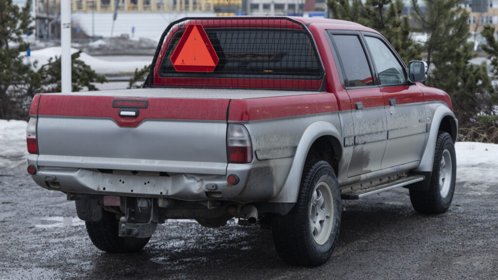 En röd lastbil står parkerad i en snöig parkeringsplats. (AI text)