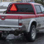 En röd lastbil står parkerad i en snöig parkeringsplats. (AI text)