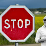 En man står bredvid en stoppskylt. (AI text)