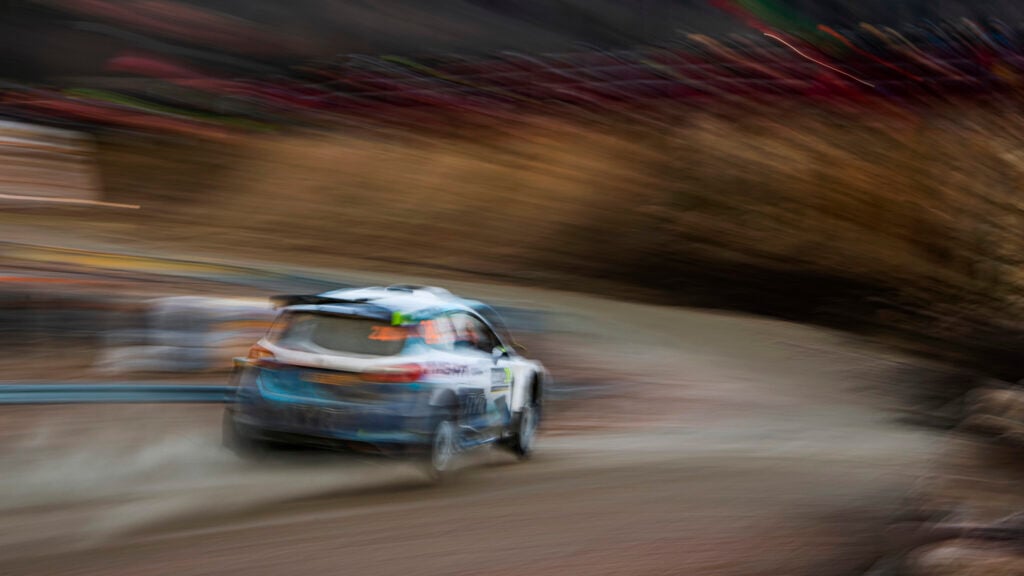 En rallybil körer längs en grusväg. (AI text)