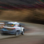 En rallybil körer längs en grusväg. (AI text)