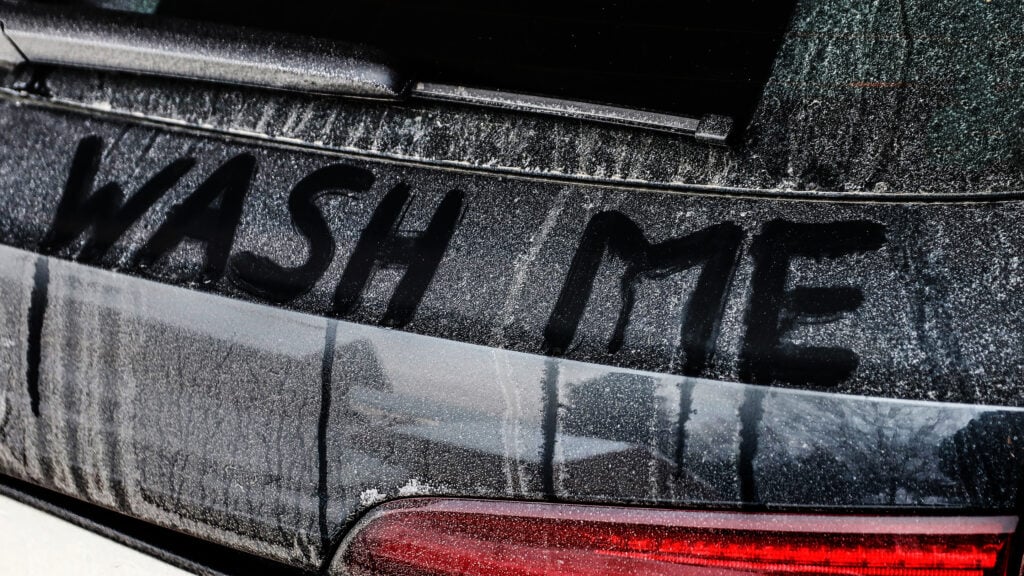 En bil med ordet "tvätta mig" skrivet på den. (AI text)