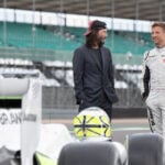 Personer poserar med en racingbil. (AI text)