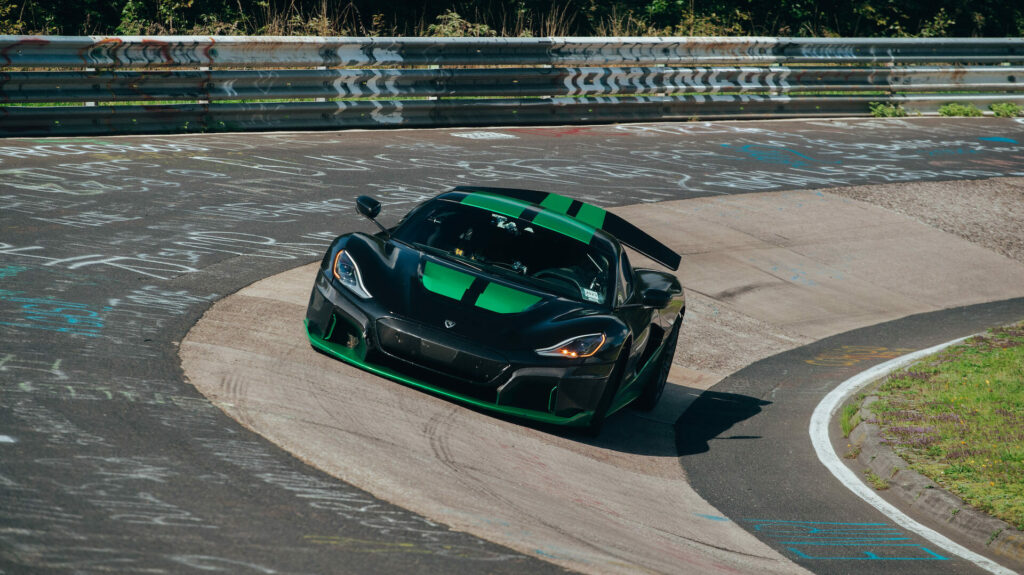 En grönt och svart sportbil kör nerför en racerbana. (AI text)
